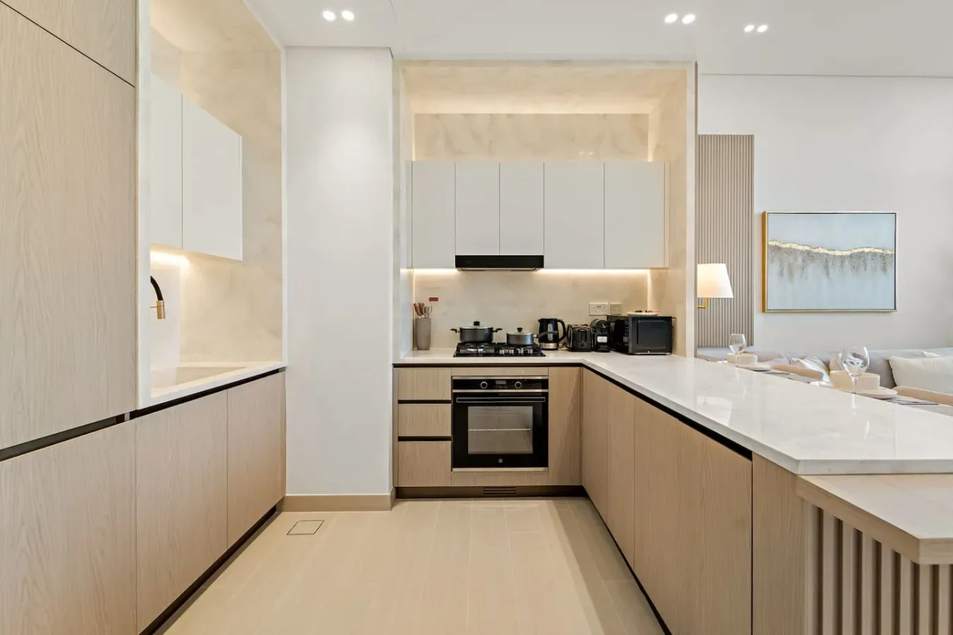 Una cocina moderna con gabinetes claros, encimeras oscuras y electrodomésticos integrados.