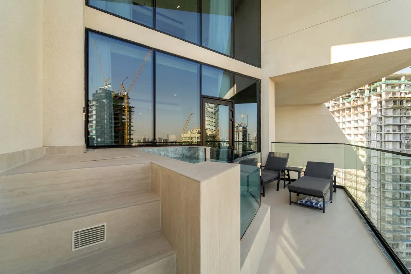 Una terraza moderna cuenta con un spa integrado junto a puertas de vidrio y asientos al aire libre.