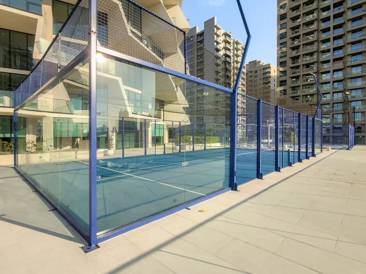 Una cancha deportiva al aire libre, cercada junto a edificios modernos.