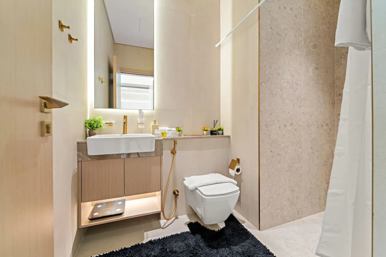 Un baño con lavabo suspendido, inodoro y zona de ducha.