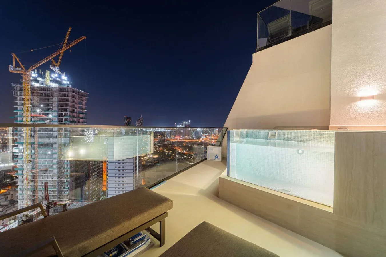 Una terraza en la azotea ofrece vistas de un horizonte urbano iluminado por la noche.