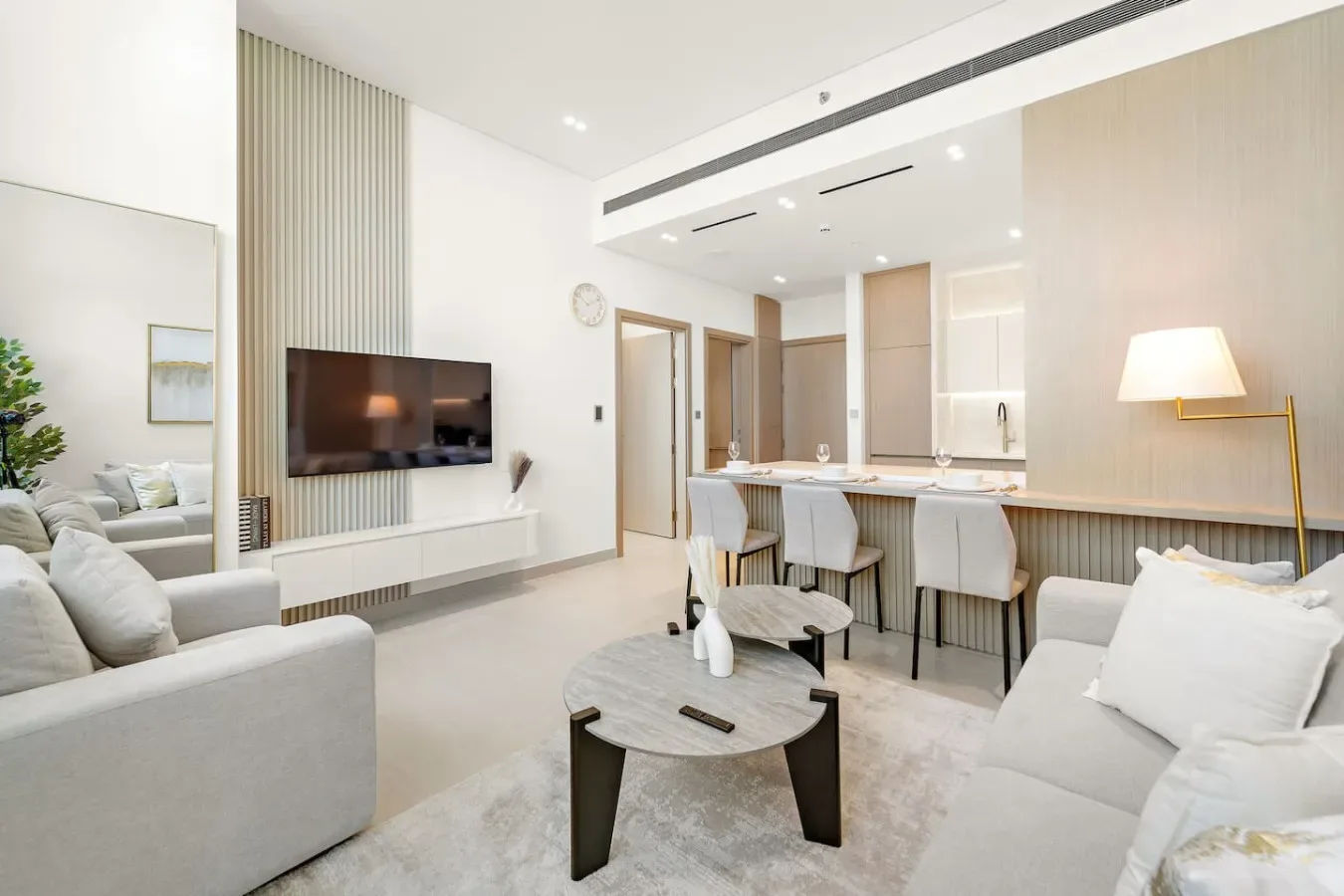 Una luminosa sala de estar de concepto abierto con asientos, televisor y barra de cocina.