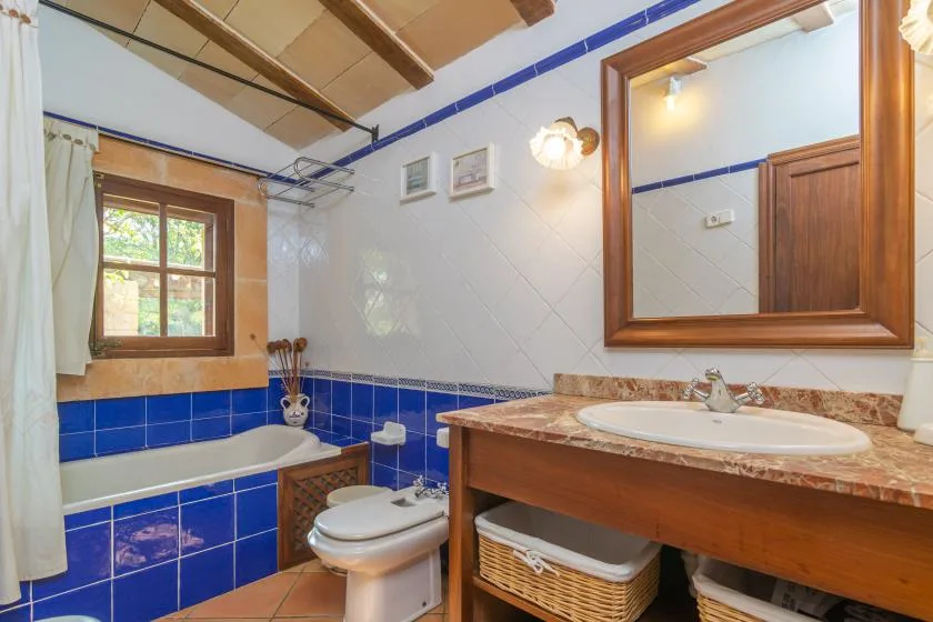 A tiled bathroom with a bathtub, toilet, and wooden vanity.