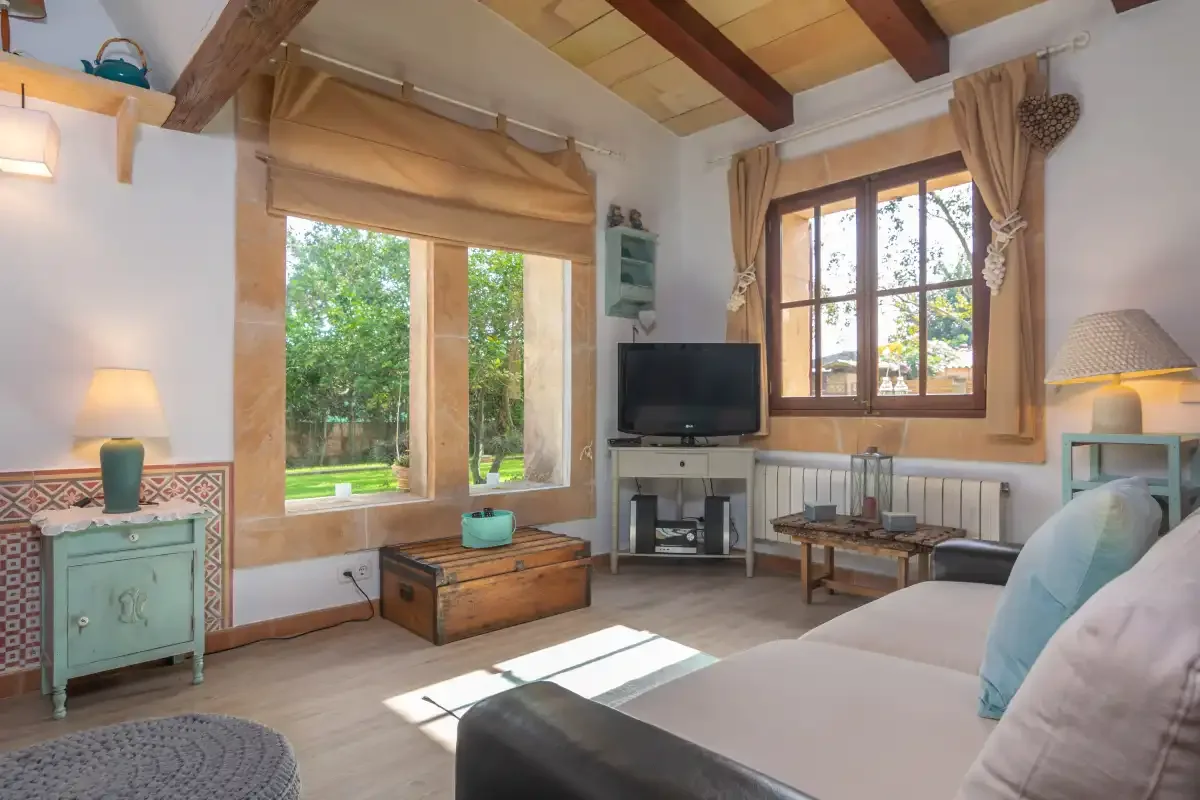 A bright living room with large windows, a television, and seating.