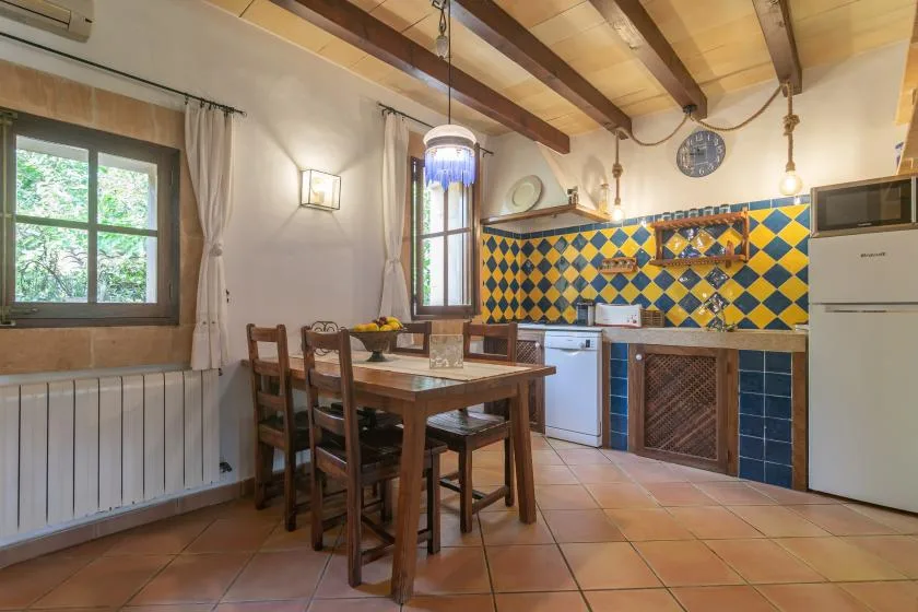 A rustic kitchen with a wooden dining table and colorful tiled backsplash.