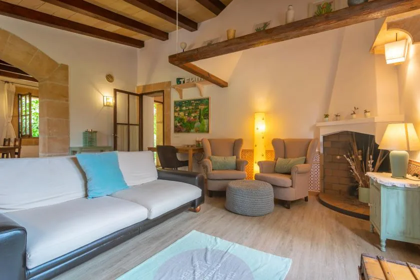 A living room with seating, a fireplace, and exposed ceiling beams.