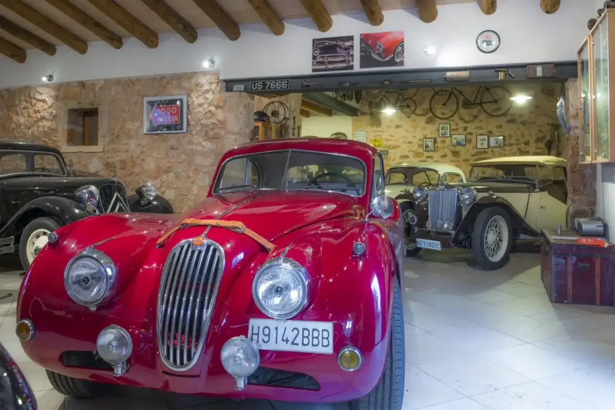 A vintage car showroom displays several classic cars, including a red car in front.