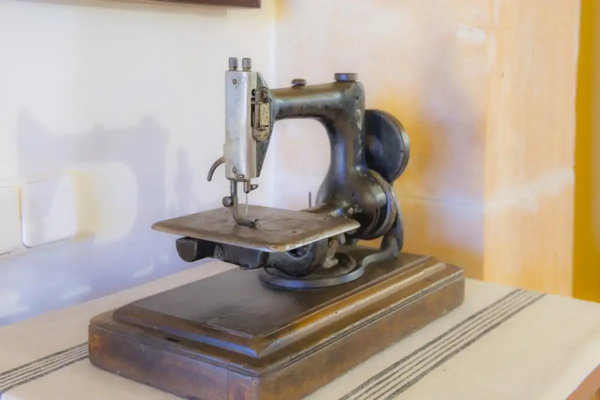 An old sewing machine sits on a table against a pale wall.