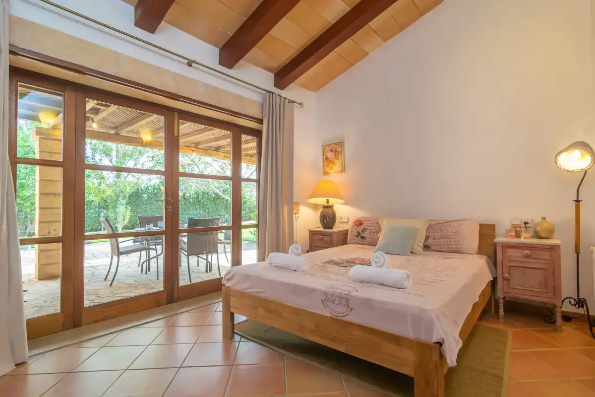 A bedroom with a double bed beside large glass doors opening onto a patio.