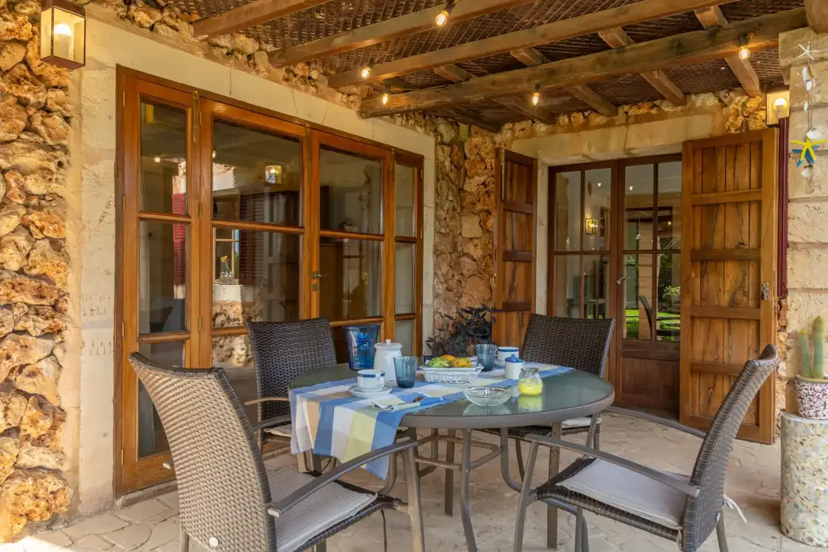 A covered outdoor dining area with a round table and surrounding seating.