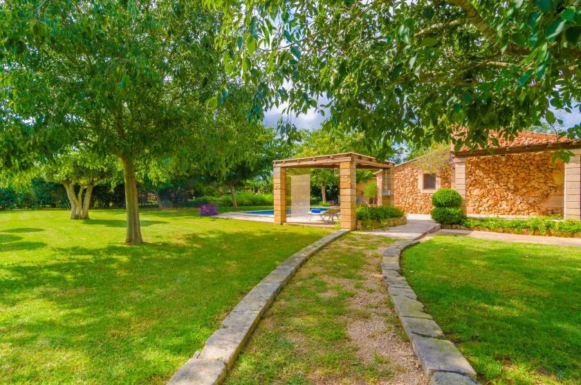 A landscaped garden with a stone path leading toward a wooden pergola.