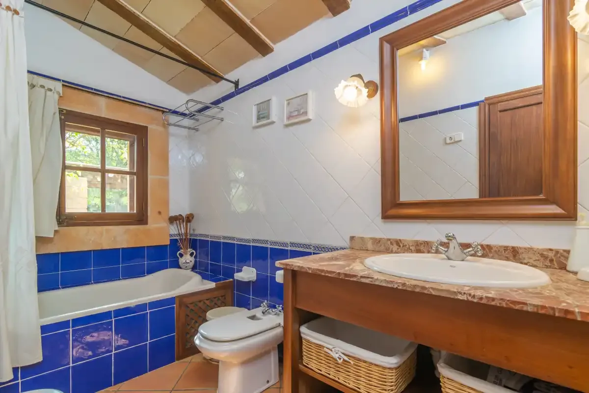A tiled bathroom with a bathtub, toilet, and wooden vanity.