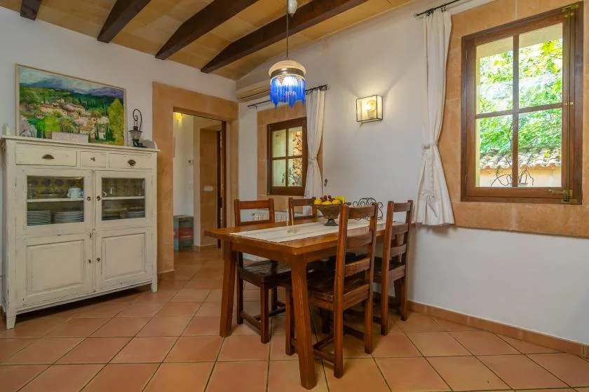 A dining room with a wooden table and chairs beneath exposed ceiling beams.