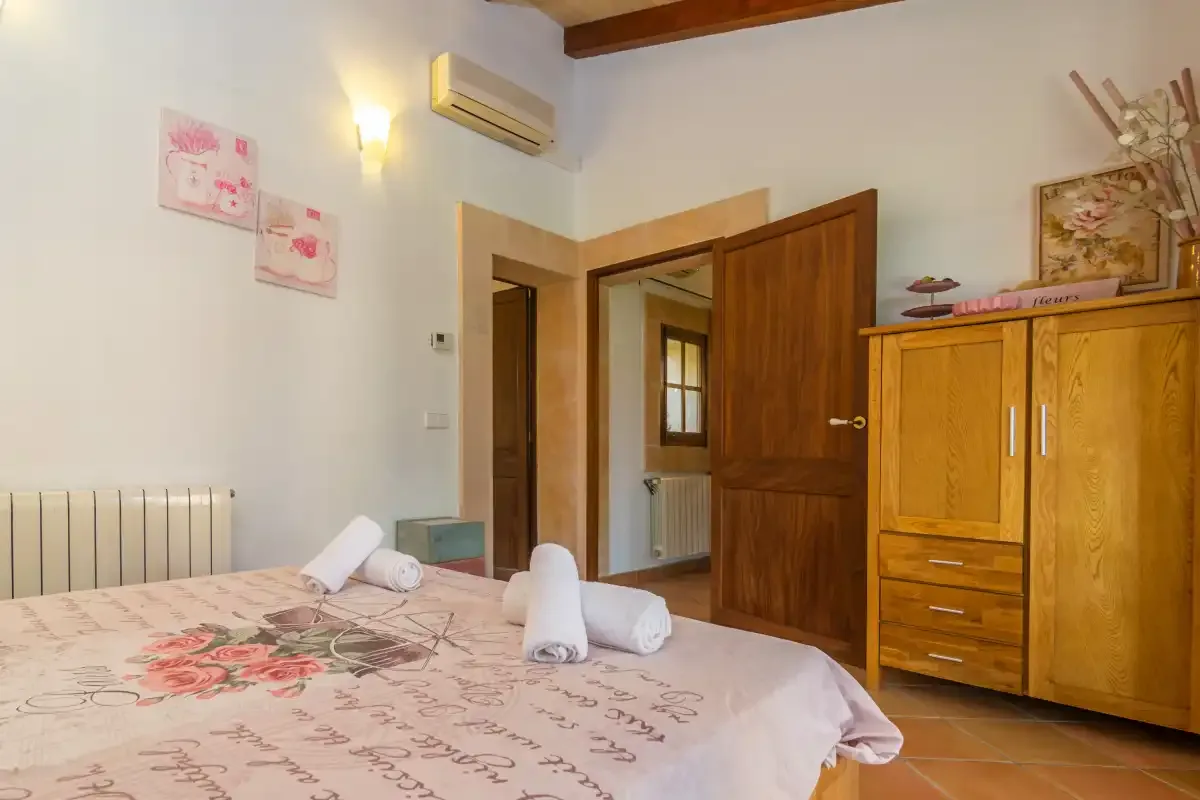 A bedroom with a bed, wooden wardrobe, and open doorway.