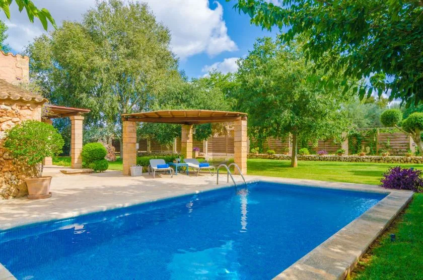 Outdoor swimming pool beside a shaded seating area and garden.