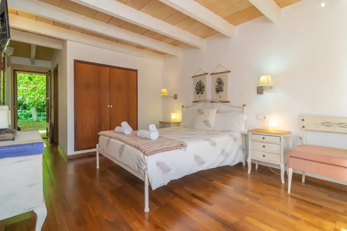 A bedroom with a double bed, wooden flooring, and exposed ceiling beams.