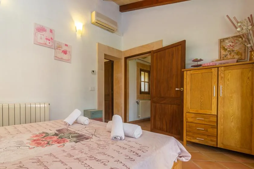 A bedroom with a bed, wooden wardrobe, and open doorway.