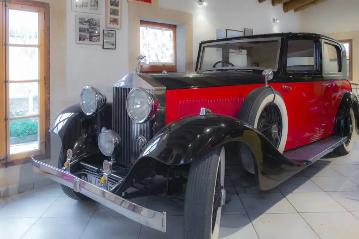 A vintage red and black car is displayed in a bright indoor room.