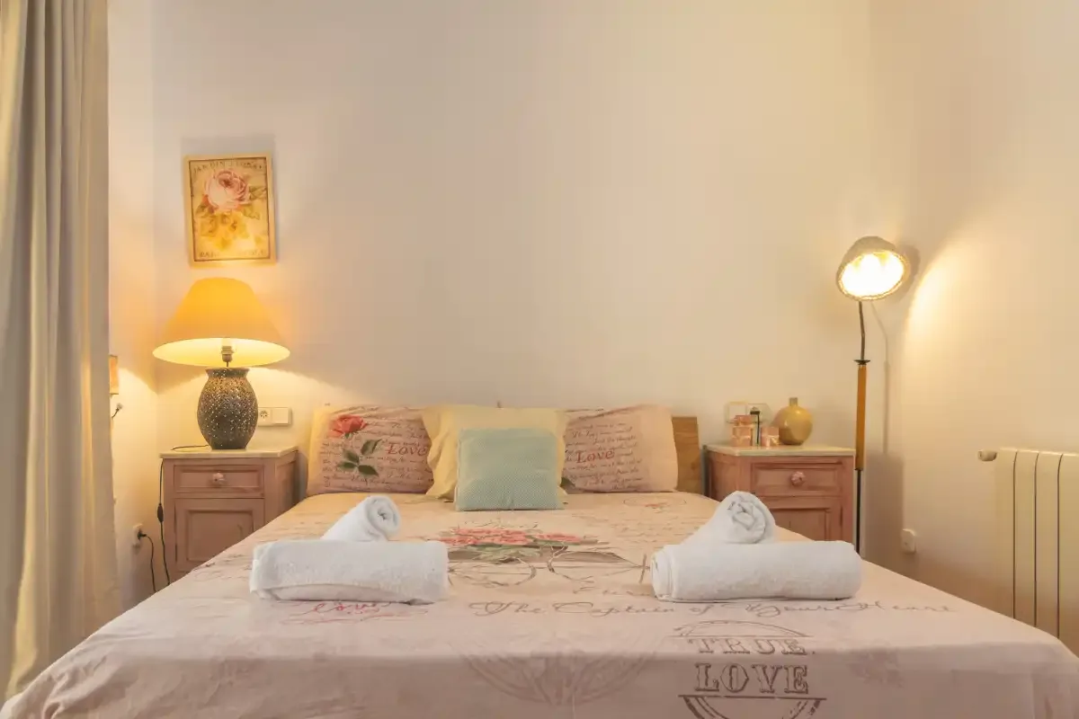 A bedroom with a double bed, bedside tables, and warm lamps.