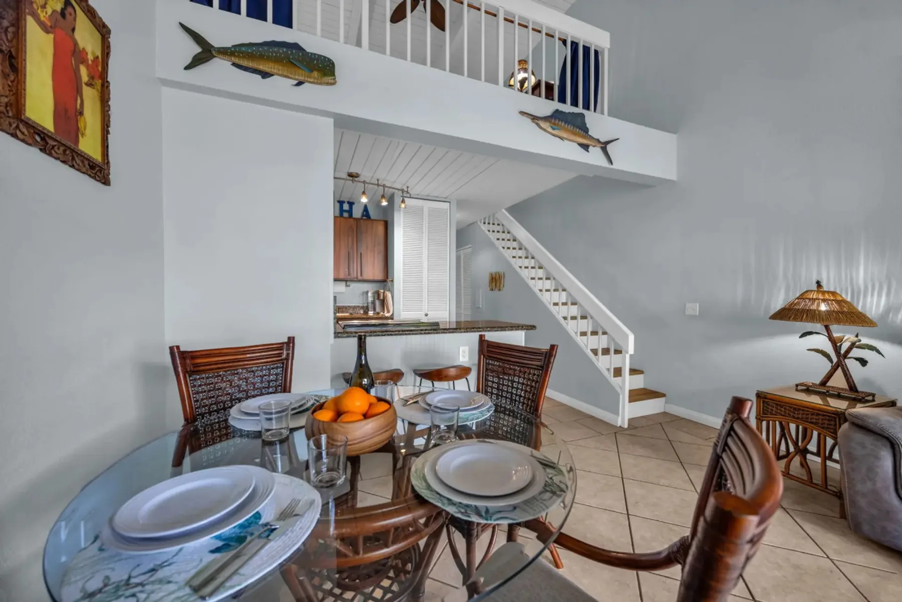 A dining area with glass tables and a staircase leading to an upper landing.