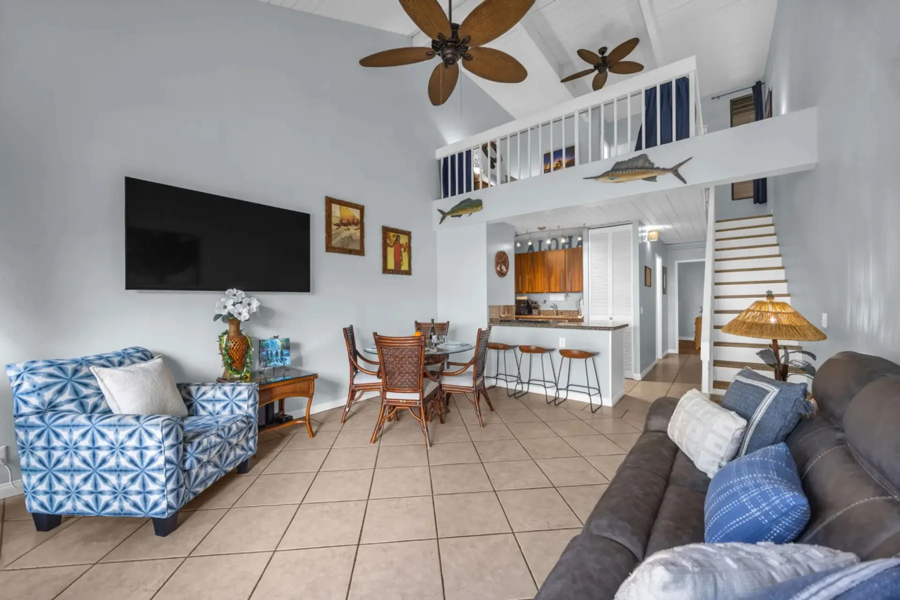 A bright living area with seating, a dining table, and a kitchen beyond.