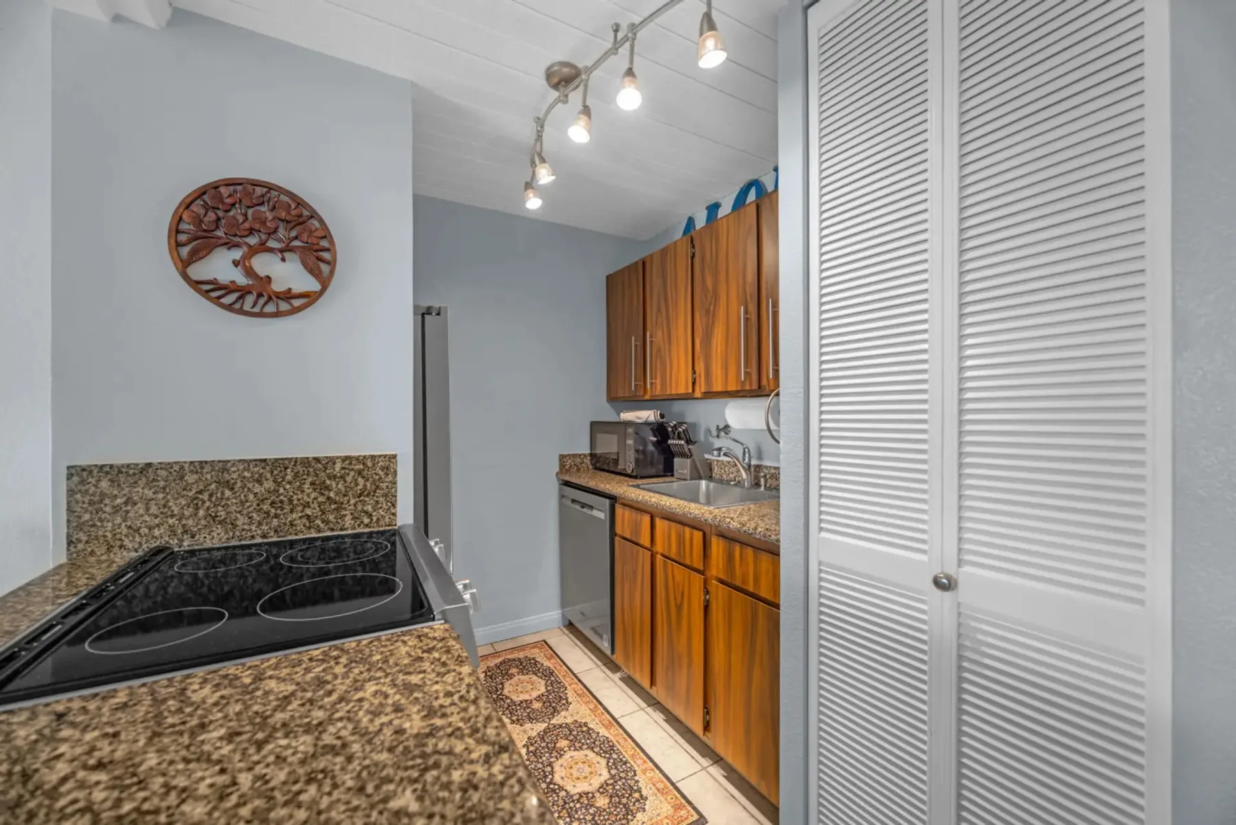 A compact kitchen with wood cabinetry, a countertop, and a cooktop.