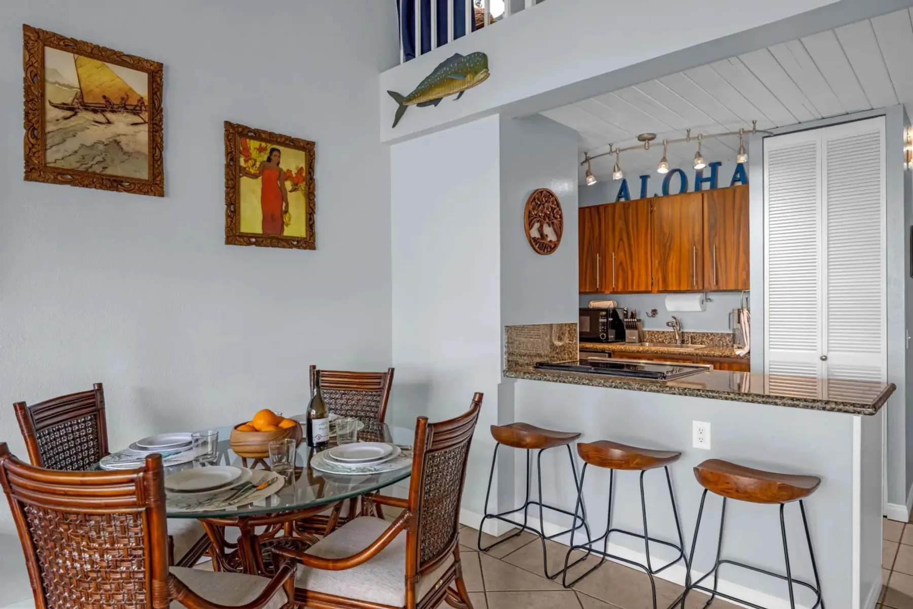 A dining area with a glass table and counter seating beside the kitchen.