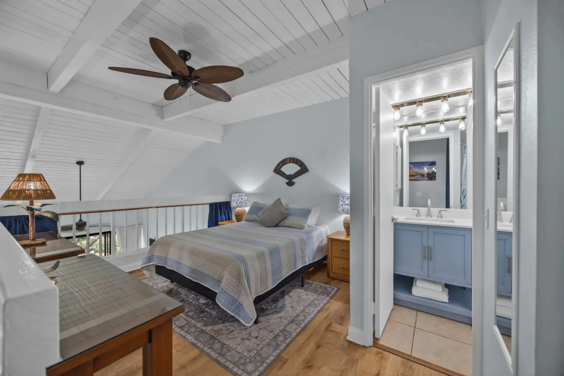A bedroom with a bed beneath a sloped ceiling and an adjoining bathroom.