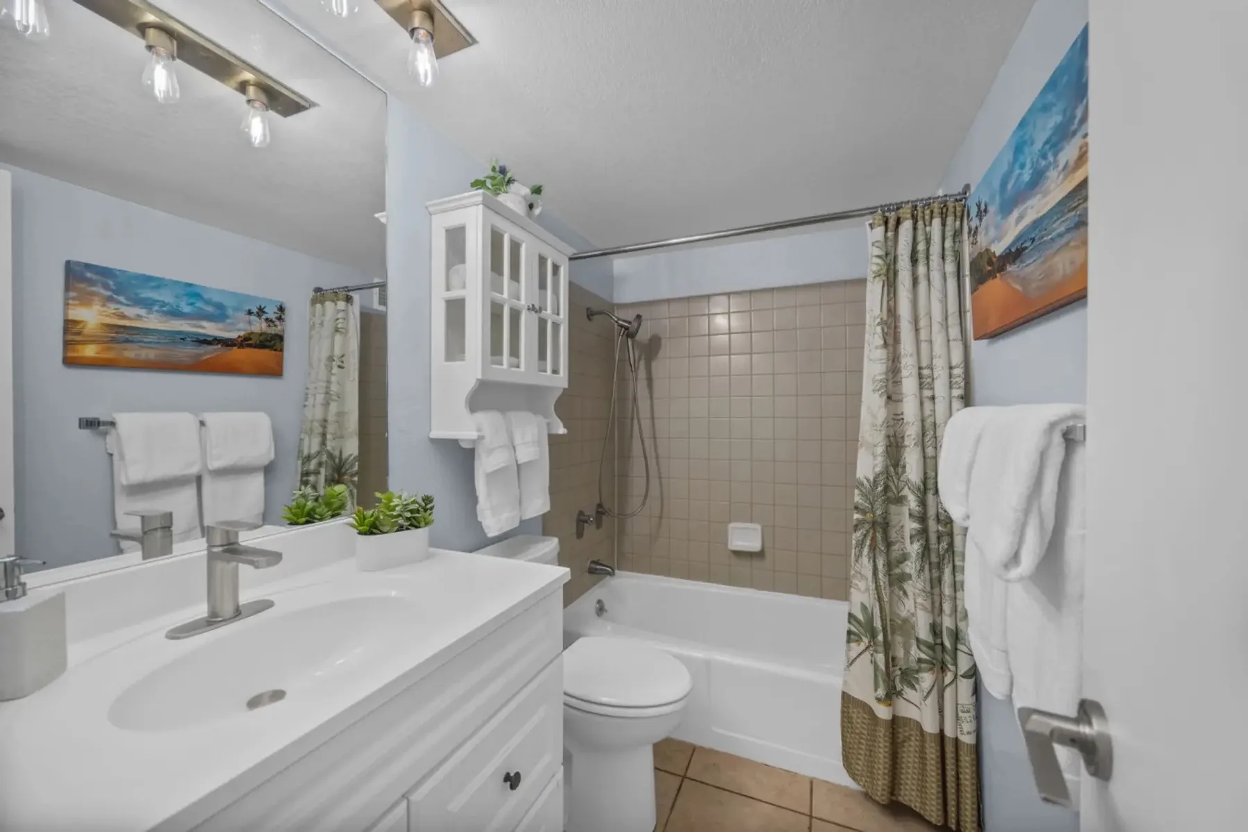 A bathroom with a bathtub, shower curtain, and sink vanity.