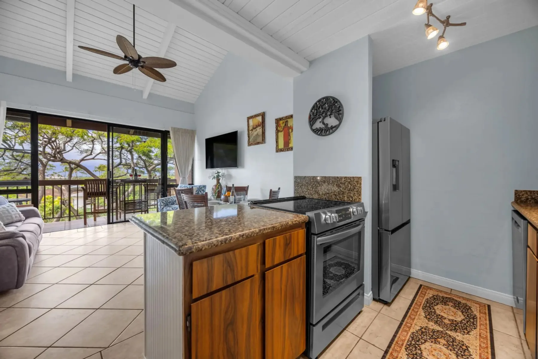 A bright kitchen with a central island and glass doors opening onto a balcony.