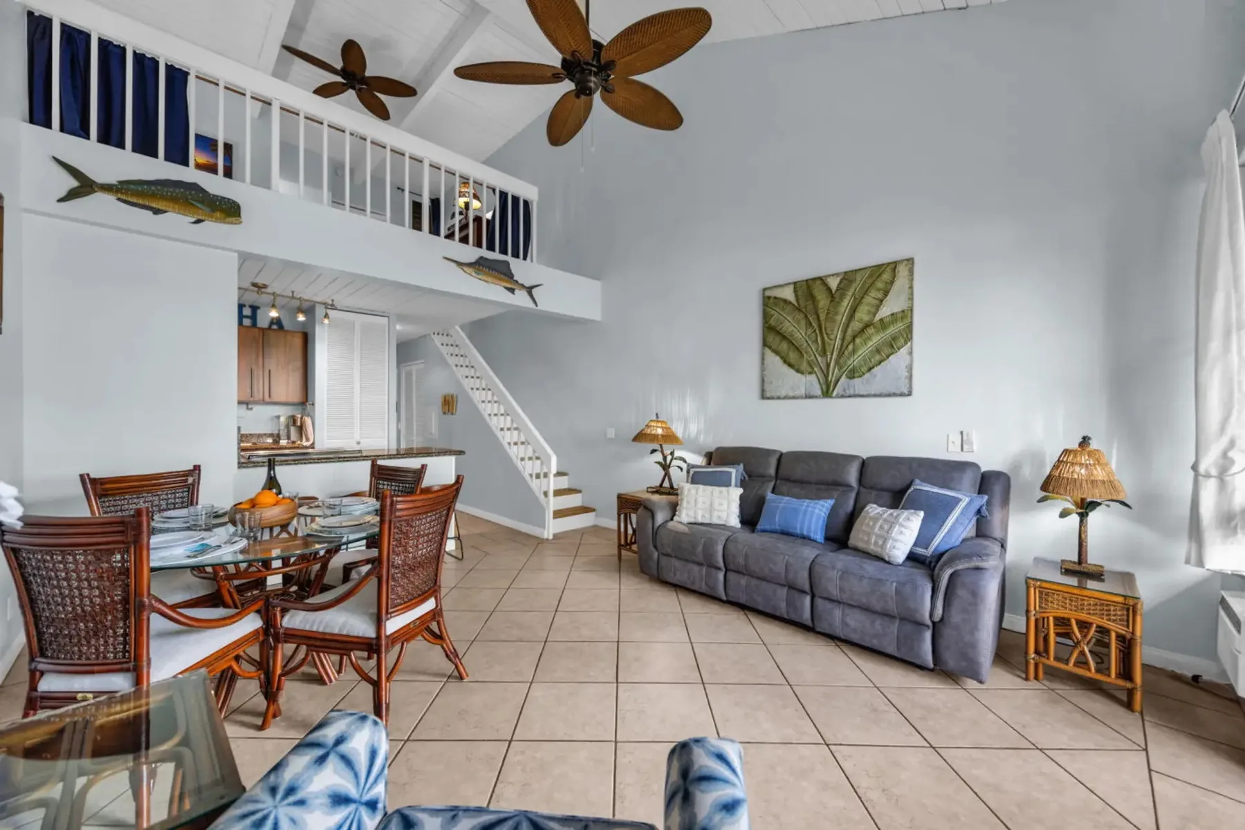 A bright living and dining area with a sofa, dining table, and lofted sleeping space.