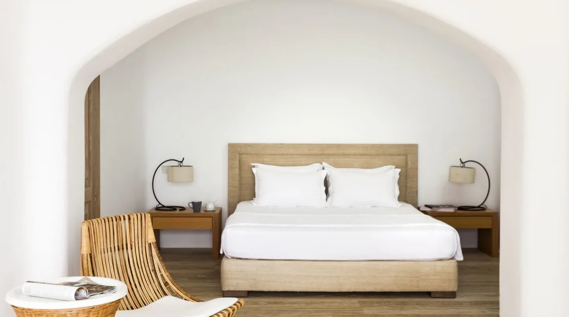 A bedroom with a bed beneath a wide arched alcove.