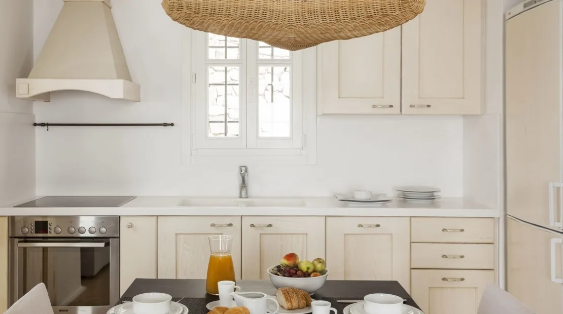 A bright white kitchen with a central window and countertop.