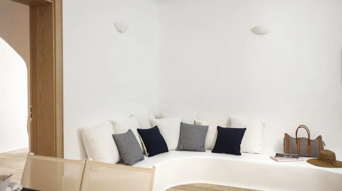 A bright living area with a curved white seating nook and dark cushions.