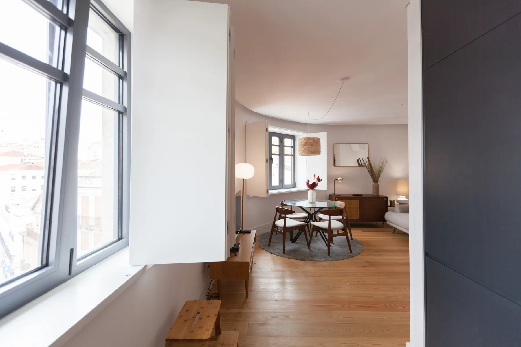 A bright dining area with a wooden table beside large windows.