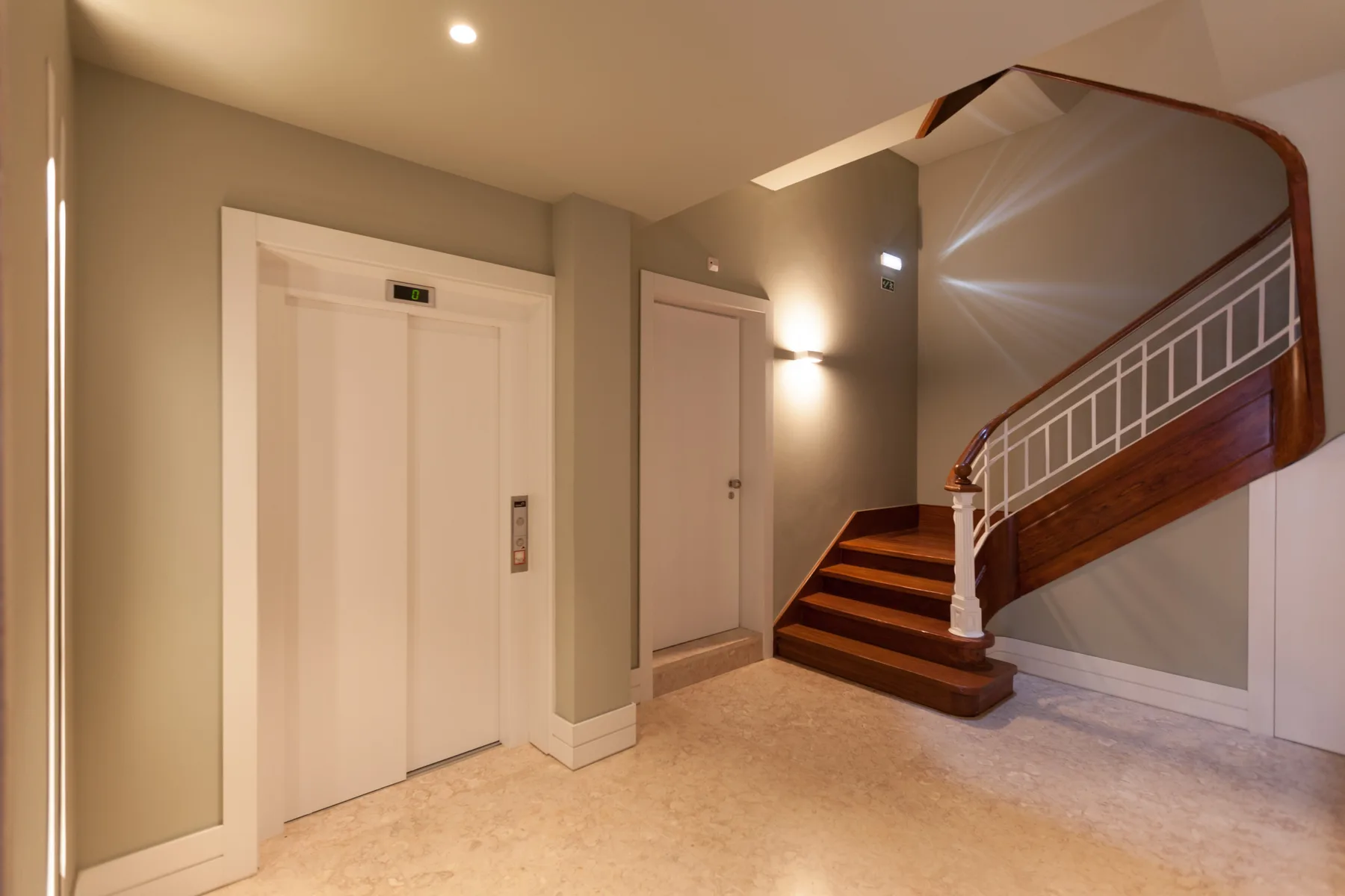 An indoor stairwell with a curved staircase and an elevator.