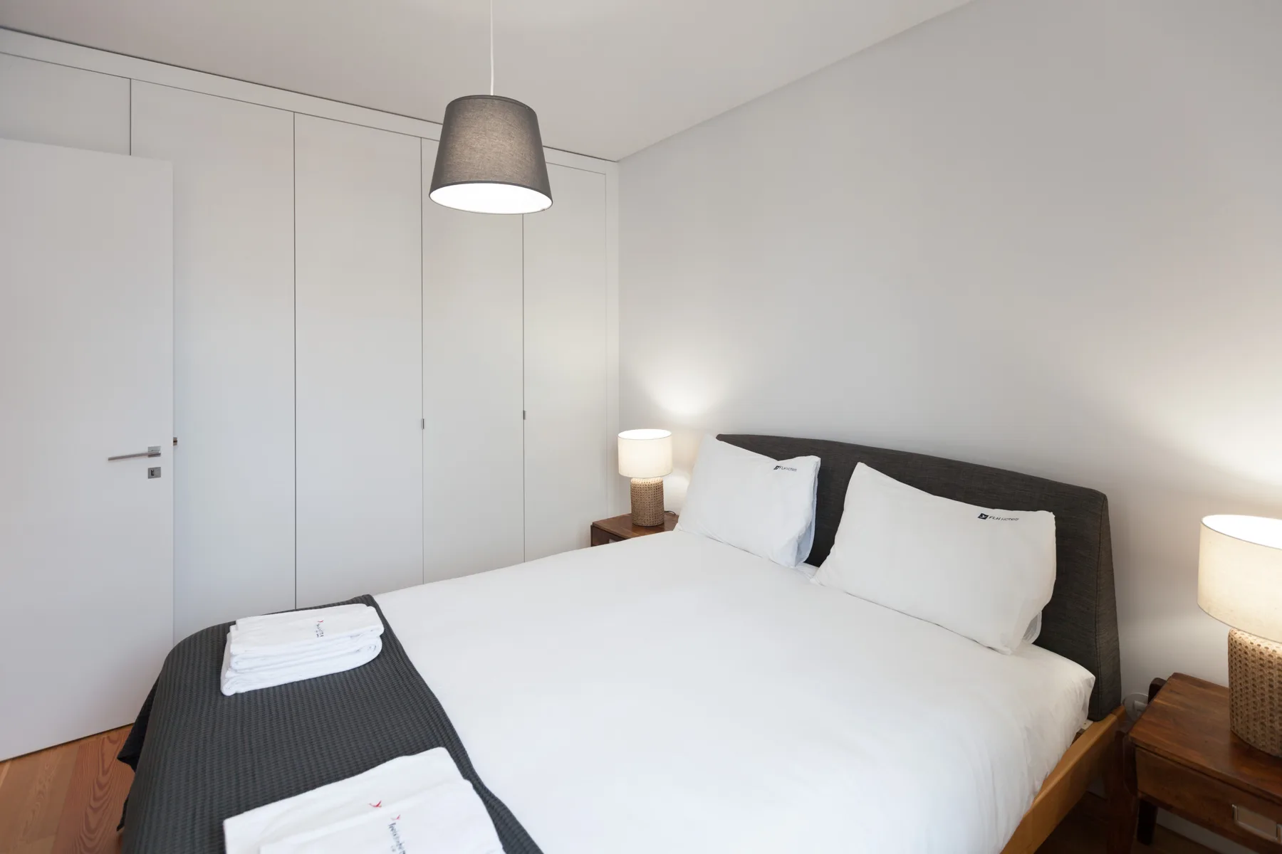 A bedroom with a neatly made bed and bedside lamps.