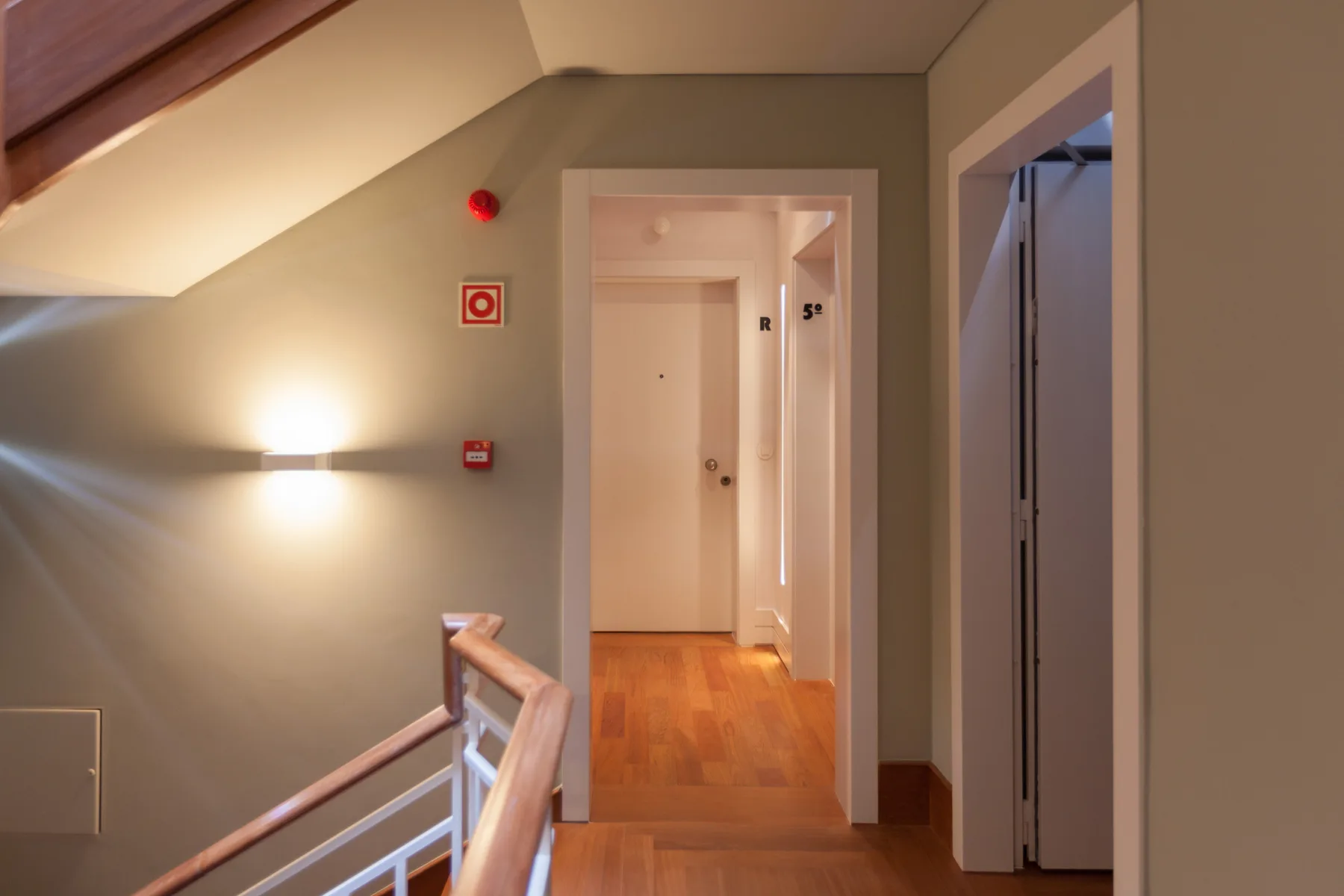 An interior hallway with a doorway opening onto a wood-floored corridor.