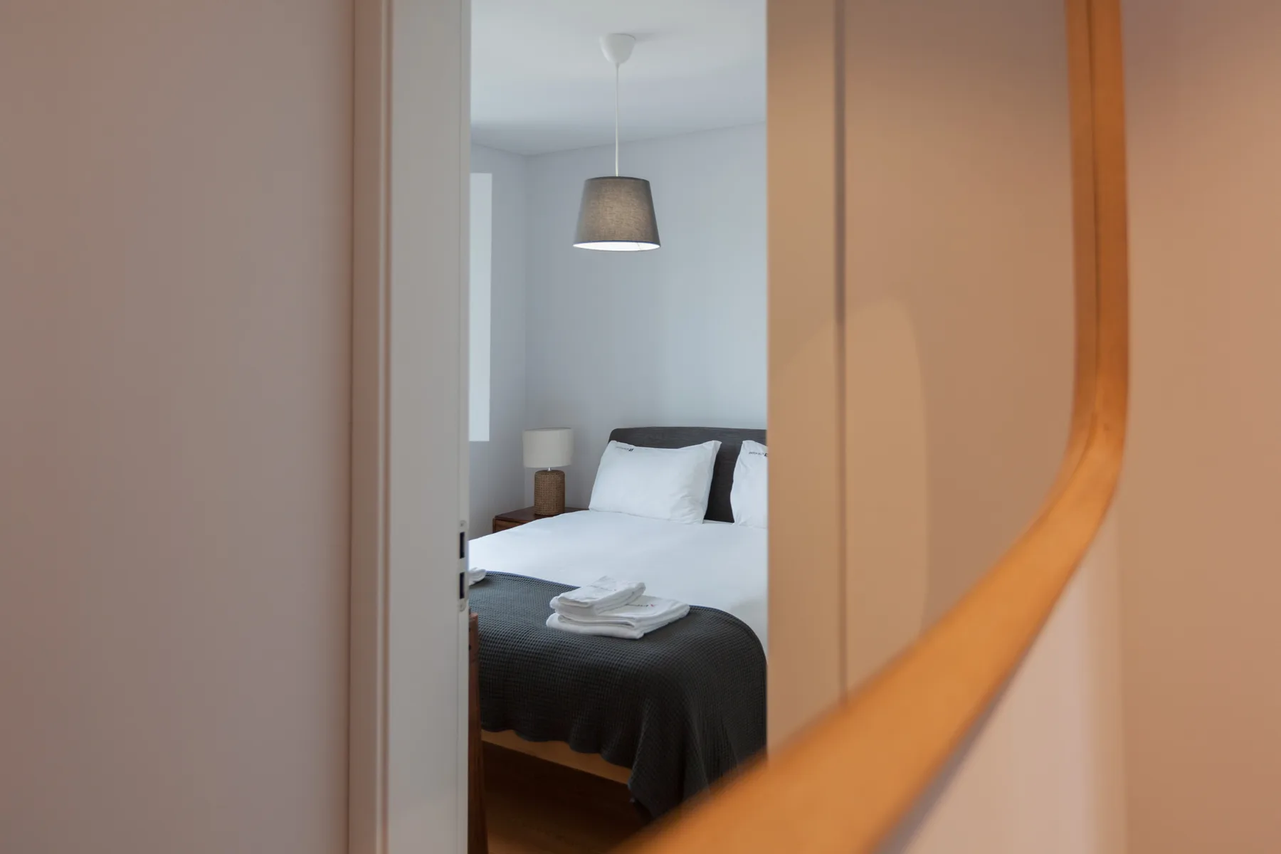 A bedroom is visible through an open doorway, with a neatly made bed.