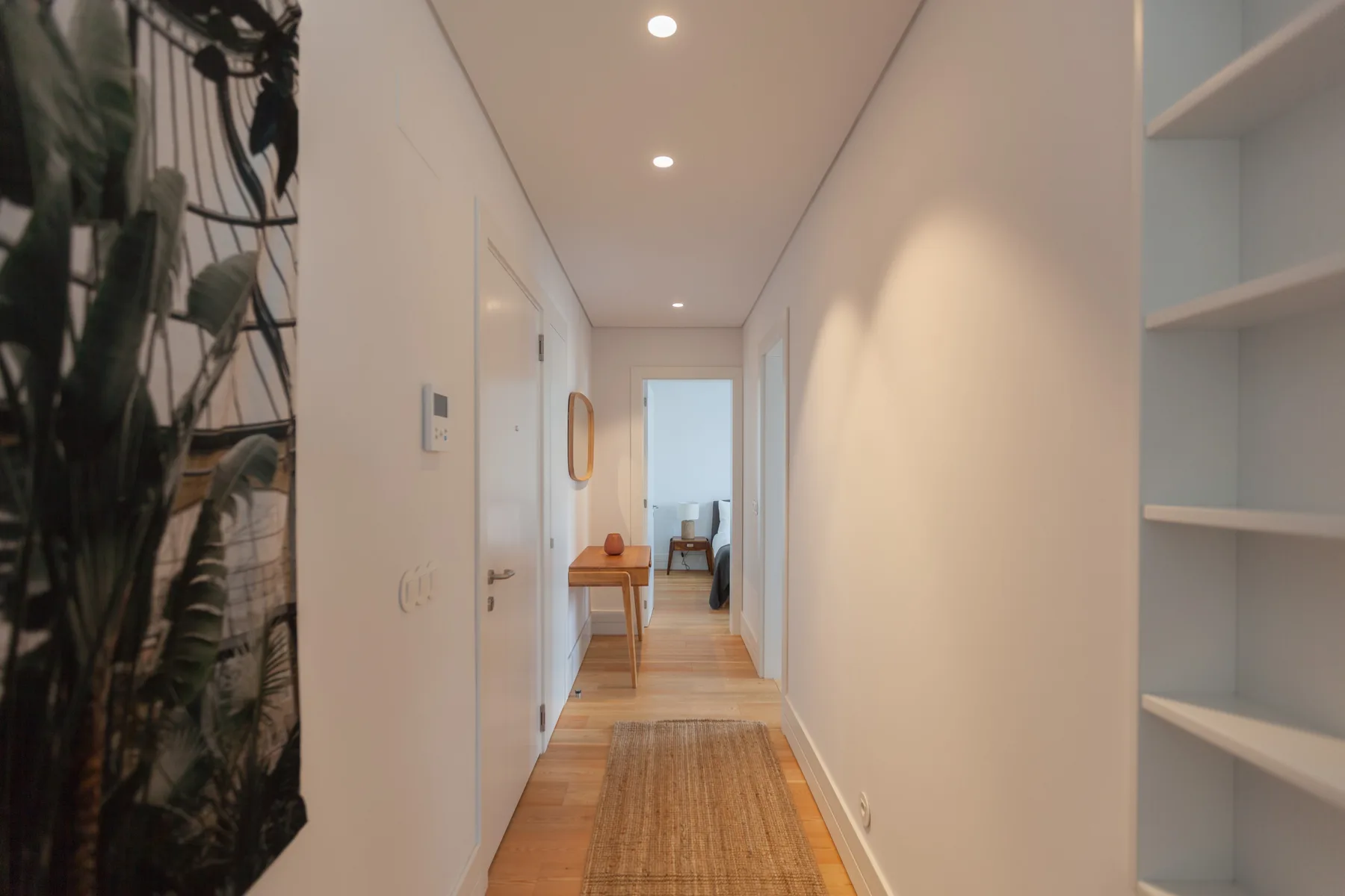 A bright hallway with wood flooring and built-in shelves.