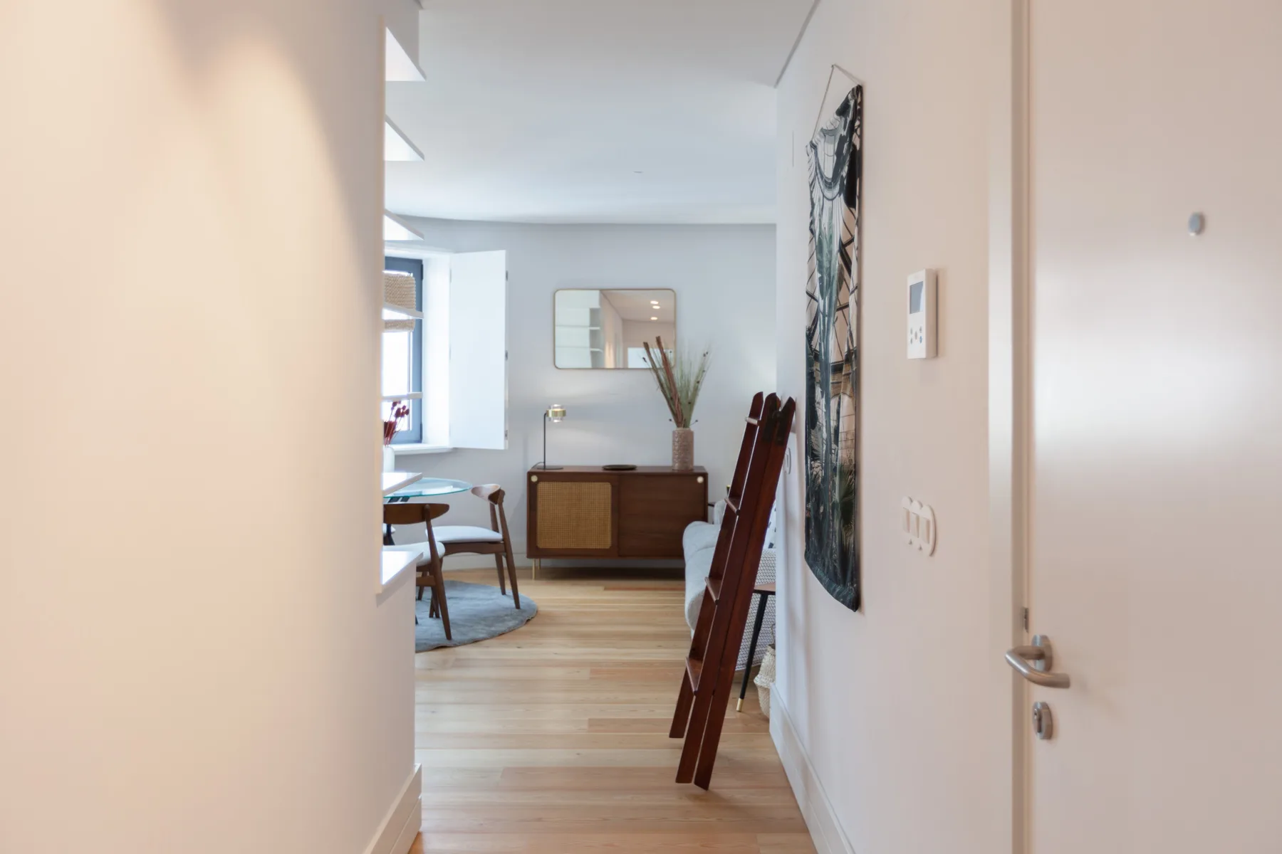 A hallway opens into a dining area with a wooden table and chairs.