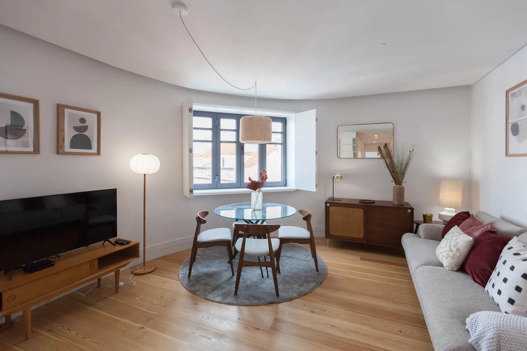 A bright living room with a dining table beside the window and a seating area.