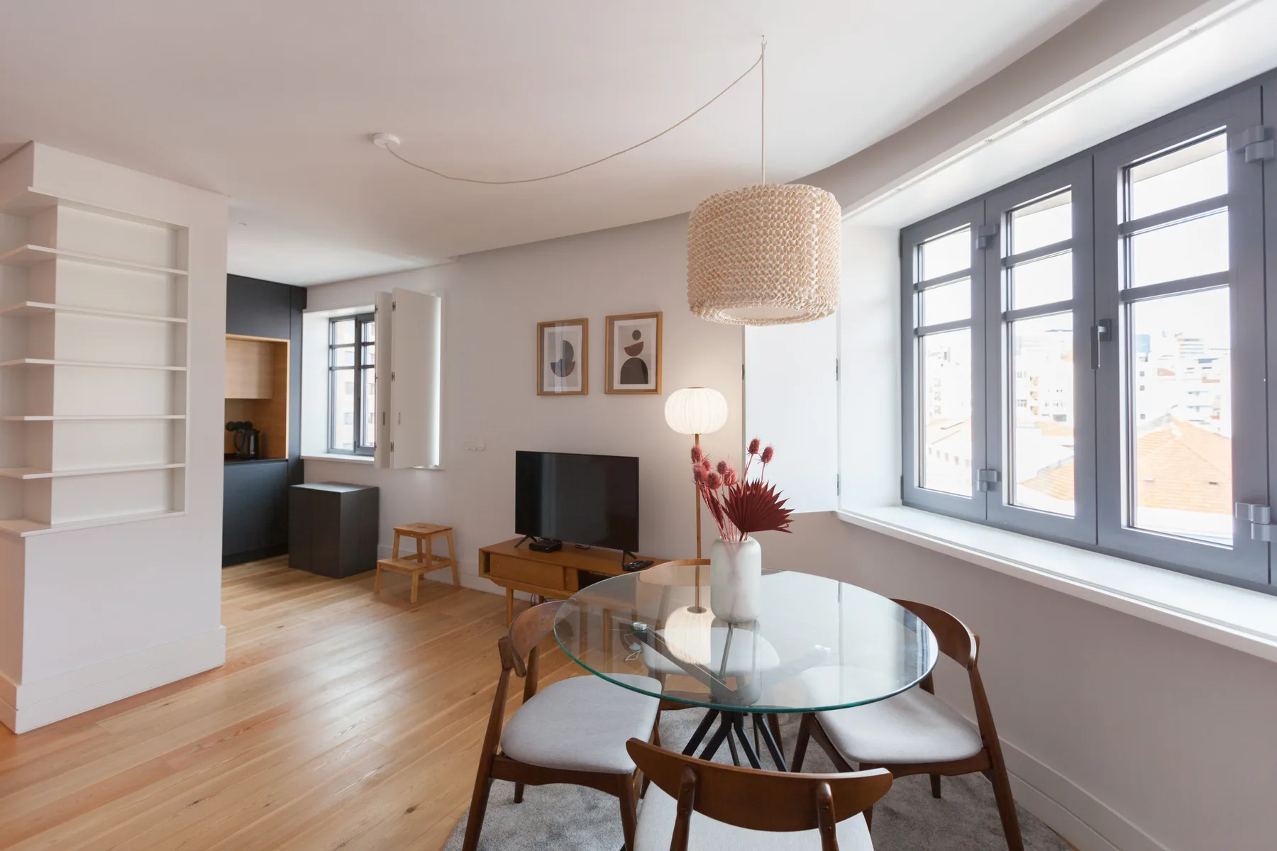 A bright living and dining area with a television and large windows.