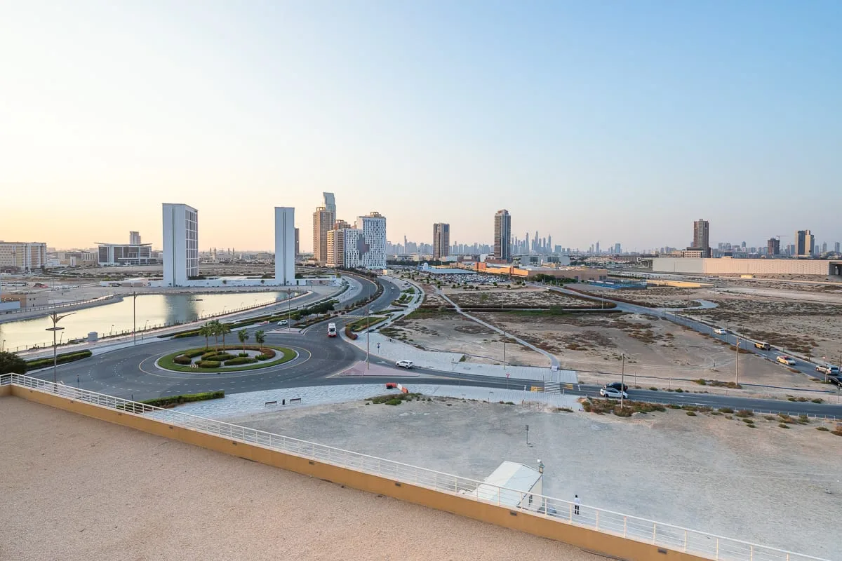 City buildings and curving roads are visible beyond a rooftop terrace.