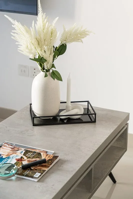 A bright room with a vase of flowers and a candle on a table.