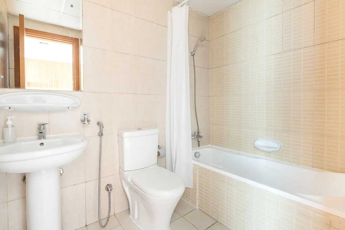 A bright bathroom with a sink, toilet, and bathtub behind a shower curtain.