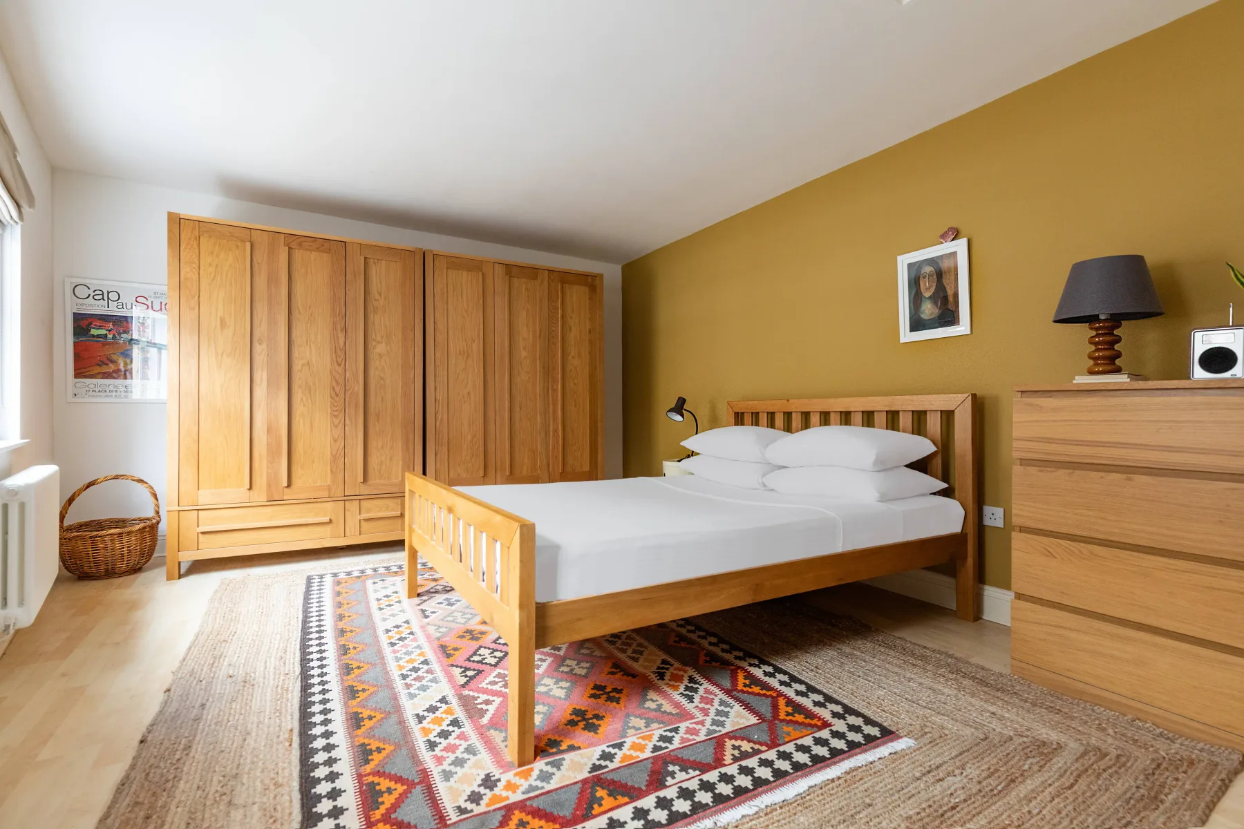 A bedroom with a wooden bed, wardrobe, and patterned rug.