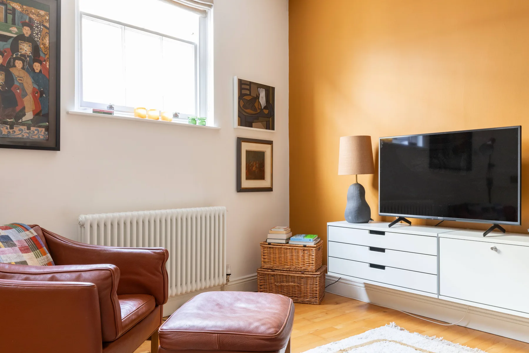 A living room with a television, seating, and a bright window.