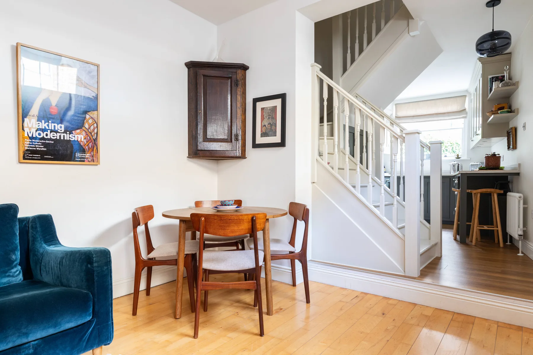 A dining area with a wooden table and seating beside a staircase.