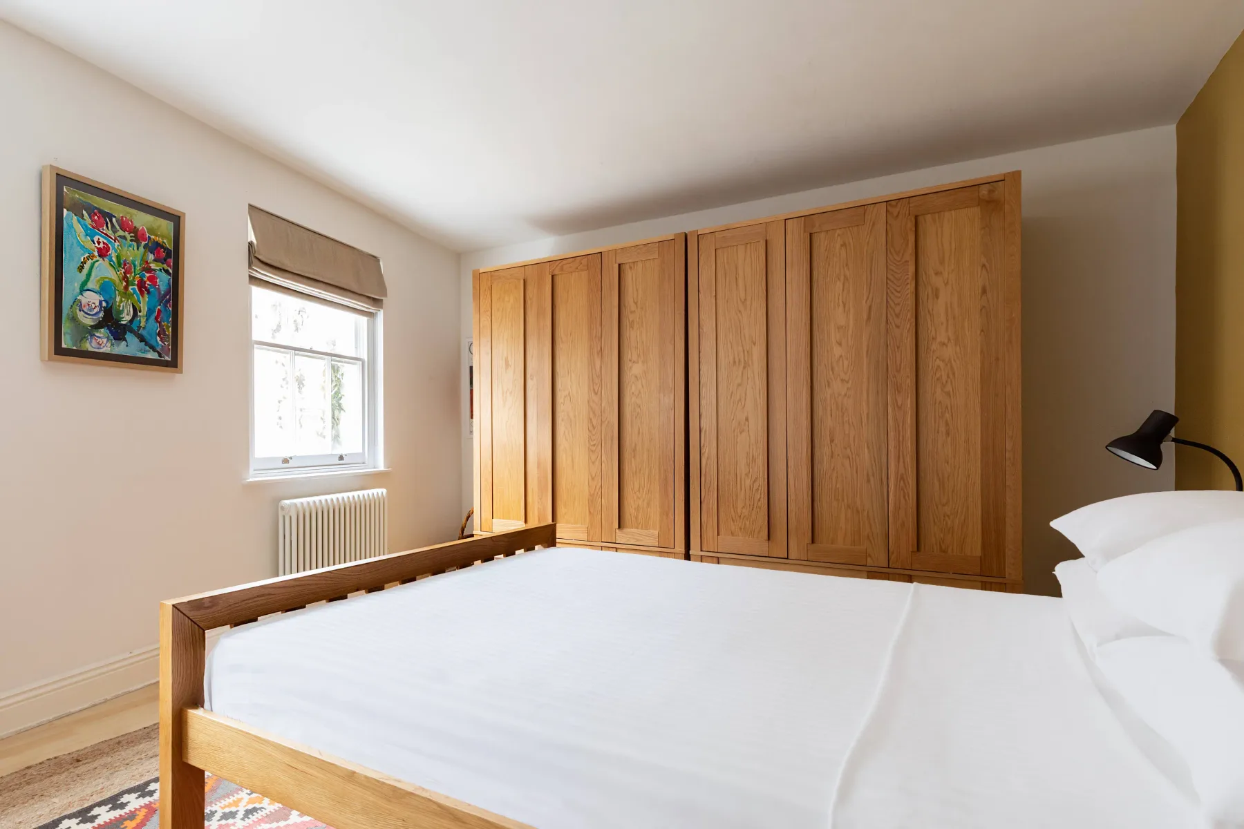 A bedroom with a white bed and wooden wardrobes.